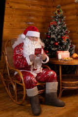 Santa Claus reading a book in a chair, with a Christmas tree behind him