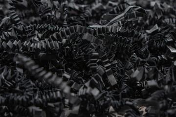Black Crinkle Paper Close-up. Detailed macro view of black crinkle paper filling material. Ideal for packaging, decoration, or gift wrapping.
