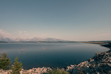 Tranquil view of Jackson Lake with Teton mountains under clear blue sky.