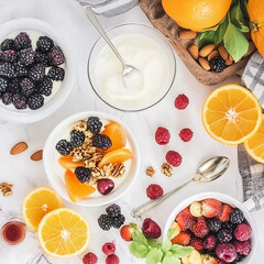 Healthy breakfast with yogurt, berries, and oranges arranged on a marble table