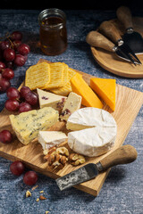 Cheese board, different types of cheese on a board, served with grapes and dried fruits.
