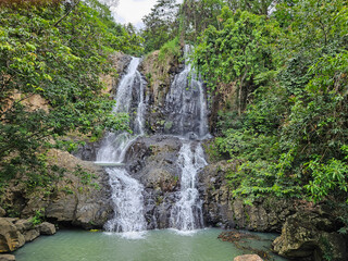 A picturesque multi-tiered waterfall, The Nest, in Nayarit, Mexico. Surrounded by vibrant green tropical jungle, its clear waters cascade over dark rocks into a tranquil pool below