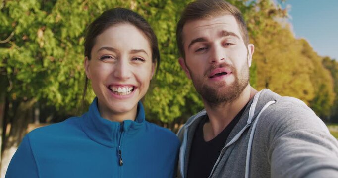 Cute Caucasian couple directly talking to camera. Discussing something. Recording video message for friends or relatives. Spending time together outdoors. Showing many different gestures with hands.