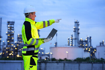 Petrochemical or refinery industry engineer working on laptop computer inspection petroleum oil refinery plant construction site. Engineering technician maintaining energy power gas system.