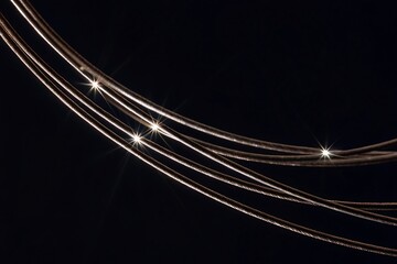 Abstract flowing lines of golden fairy lights against a dark background
