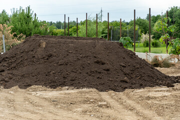 Large pile of soil in a construction site surrounded by greenery on a sunny day