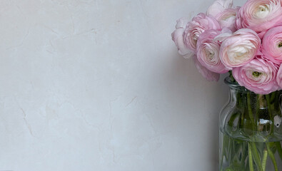 Pink ranunculus bouquet in glass vase against light background: floral decor for florists, interior designers, event planners concept of