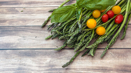 Fresh asparagus and cherry tomatoes on rustic wooden surface - concept of businesses: farmers' markets, grocery stores, farm-to-table restaurants