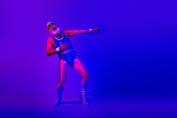 Fototapeta premium Retro fitness performer in blue jumpsuit strikes a dynamic pose under purple neon lights for lifestyle