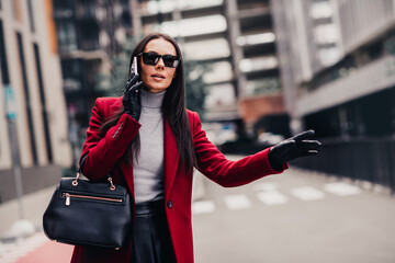 Fashionable woman in red coat and sunglass on urban street during a stylish outing, projecting...