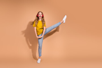 Cheerful young woman expressing joy in stylish casual outfit against beige background