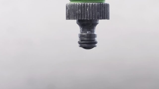 Close-up of a water droplet dripping from weathered old faucet outdoors, concept of draught