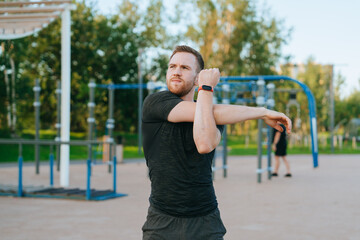 A man in sports attire performs a vigorous shoulder stretch, under a pristine sky, showcasing his commitment to health and fitness.