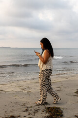 Woman on the beach taking pictures of the sunrise.