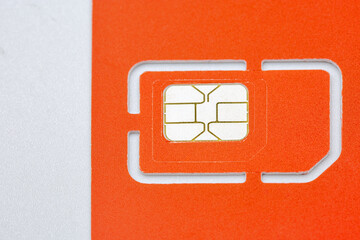 Orange SIM card with golden chip on white background closeup.