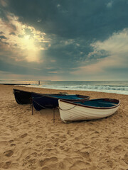 Boats on sandy beach at sunset