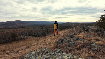 Hiking enthusiast in bright clothing views expansive valley scene with thoughtfulness, An adventurous man in yellow coat gazes across layered hills into horizon with reflective calmness