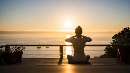 Serene woman meditating in lotus pose on wooden deck overlooking ocean at sunrise with boats in - Powered by Adobe