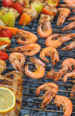 Shrimp, vegetables and fish are fried on a barbecue. Selective focus.