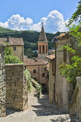 Town square in Sant'Agata Feltria, Italy, with historic buildings and the dramatic Rocca Fregoso fortress. © Marcel