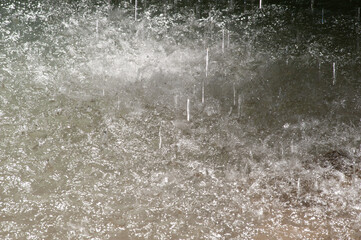 A blurred natural background of drops and streams of falling water from a waterfall.