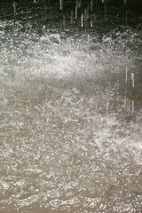 A blurred natural background of drops and streams of falling water from a waterfall.