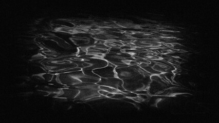 Wave streaks on the water surface, grainy background in a dark frame.