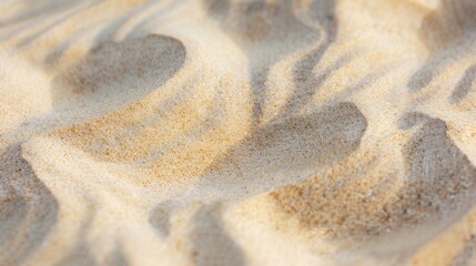 Obraz premium Close-up of textured sand with gentle waves and patterns. The light creates soft shadows, highlighting the natural beauty of the beach environment.