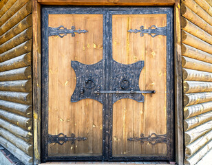 Wooden gate with forged massive metal hinges