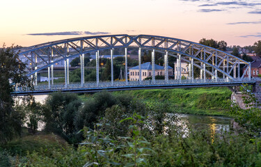 Steel arch bridge across the Msta river in summer evening. Built in 1905. Borovichi, Russia