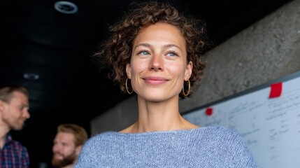 Energetic Middle Eastern woman in cozy blue sweater exudes confidence, sparking innovation during International Women's Day brainstorming session