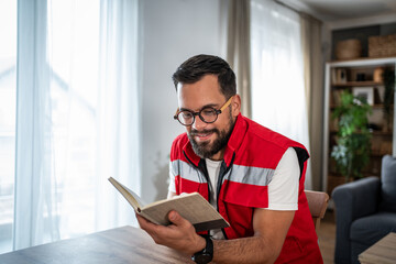 Fototapeta premium Paramedic man relaxing at home reading a book