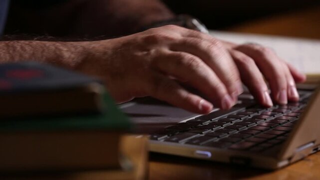 Close-up of hands comparing an old book and typing rapidly on a modern laptop. Blending history, research, and digital workflow.