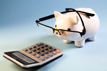 Piggy bank with glasses and calculator on a blue background.