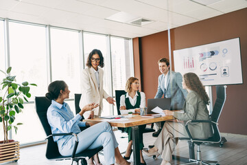 Group of professionals collaborating in a modern office workspace with a presentation and business documents