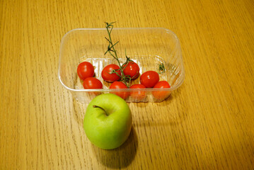 Fresh cherry tomatoes and green apple on a wooden table