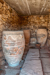 Ancient clay storage jars at archaeological site of Phaistos, Crete, Greece, showing Minoan palace ruins and traditional pottery in stone room
