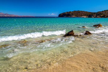 Voulisma Beach in Crete, Greece, with turquoise sea, golden sand, and rocky coast under bright blue summer sky in Mediterranean landscape