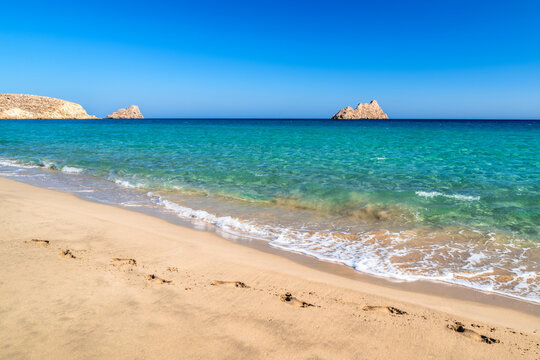 Footprints on sandy beach at Mazida Ammos, Crete, Greece, with turquoise sea, clear blue sky and sunny summer Mediterranean coast in natural light