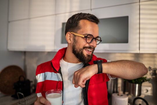 Young man smiling and checking smartwatch during morning breakfast