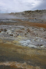 Steaming geothermal field at Hverir near Mývatn, Iceland, showing colorful mineral deposits, cracked earth and volcanic landscape shaped by geothermal activity