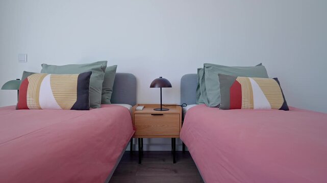 Spacious hotel guest room featuring neatly arranged twin beds with coordinated pillows and blankets, showcasing contemporary minimalist interior design and comfortable accommodation styling
