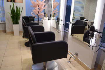 A modern hair salon interior with black chairs, large mirrors, and minimalist decor. Concept for a beauty salon professional's workspace, modern customer service
