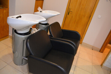 A modern hair salon interior with black chairs, large mirrors, and minimalist decor. Concept for a beauty salon professional's workspace, modern customer service