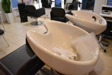 A modern hair salon interior with black chairs, large mirrors, and minimalist decor. Concept for a beauty salon professional's workspace, modern customer service