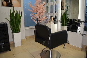 A modern hair salon interior with black chairs, large mirrors, and minimalist decor. Concept for a beauty salon professional's workspace, modern customer service