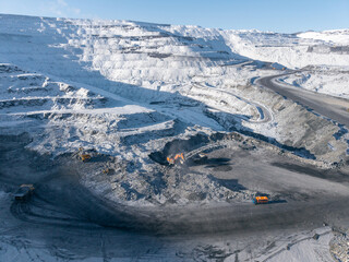 Winter landscape of open pit coal mine with machinery operations