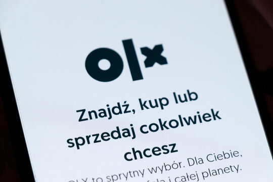 Warsaw, Poland - November 6, 2025: A smartphone screen displaying the OLX logo and text in Polish. The platform offers buying and selling options to users.