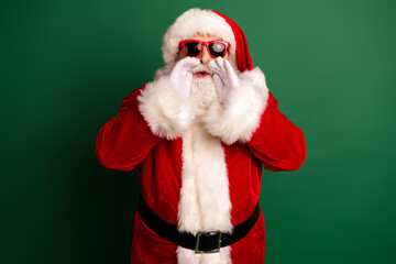 Santa in red suit with white fur robe and hat speaks through hands as a festive holiday figure for Christmas marketing