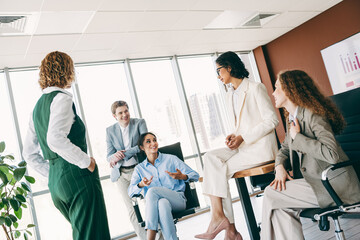 Obraz premium Group of professionals discussing projects in a stylish modern office space with diverse business attire and collaboration